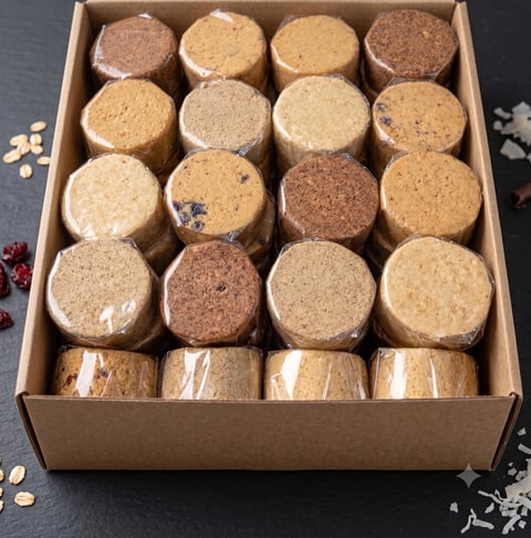 Assorted homemade cookies in a cardboard box arranged in rows, including sugar, oatmeal, and spiced varieties with some wrapped individually